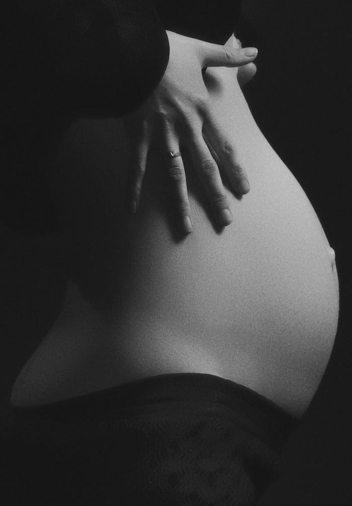 The Art of Drawing Readers In: Your attractive post title goes here Intimate black and white photo of a pregnant woman's belly with hand gently resting.