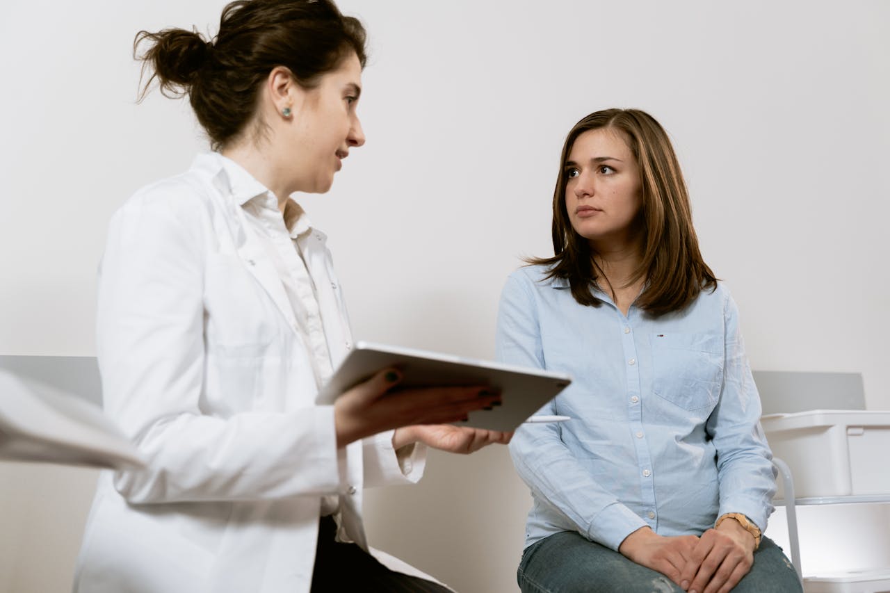 about-us A doctor consults with a pregnant patient discussing healthcare options in a medical facility.